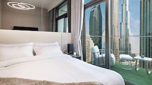 A modern hotel room with a large bed, a view of a city skyline, and a balcony with seating. - The Burj Crown Stays by UniDwellers Holiday homes (Dubai)