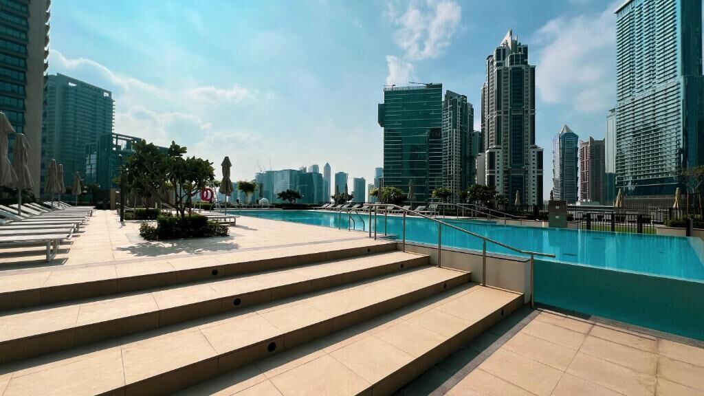 A poolside area with steps leading to a pool, surrounded by modern buildings.