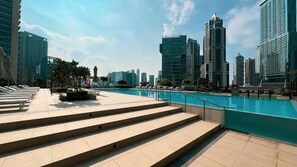 Zona de piscina con escalones que bajan a ella, rodeada de edificios modernos.