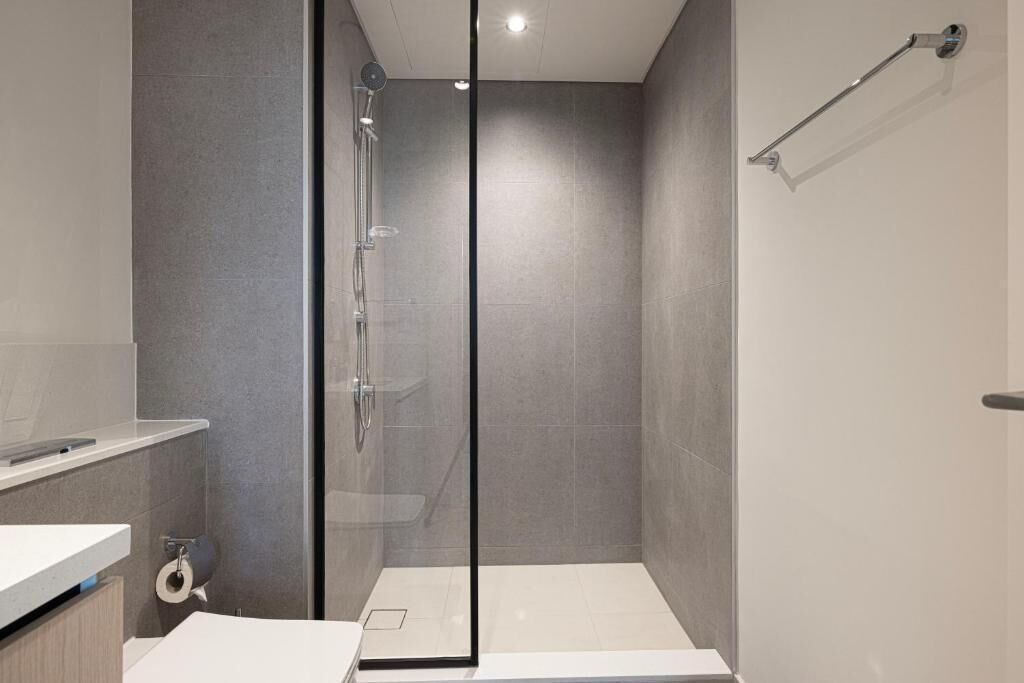 Une salle de bain moderne avec une douche à parois de verre, un lavabo blanc et un porte-serviettes.