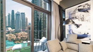 A modern living room with a large window, a sofa, a chair, and a lamp. - The Burj Crown Stays by UniDwellers Holiday homes (Dubai)