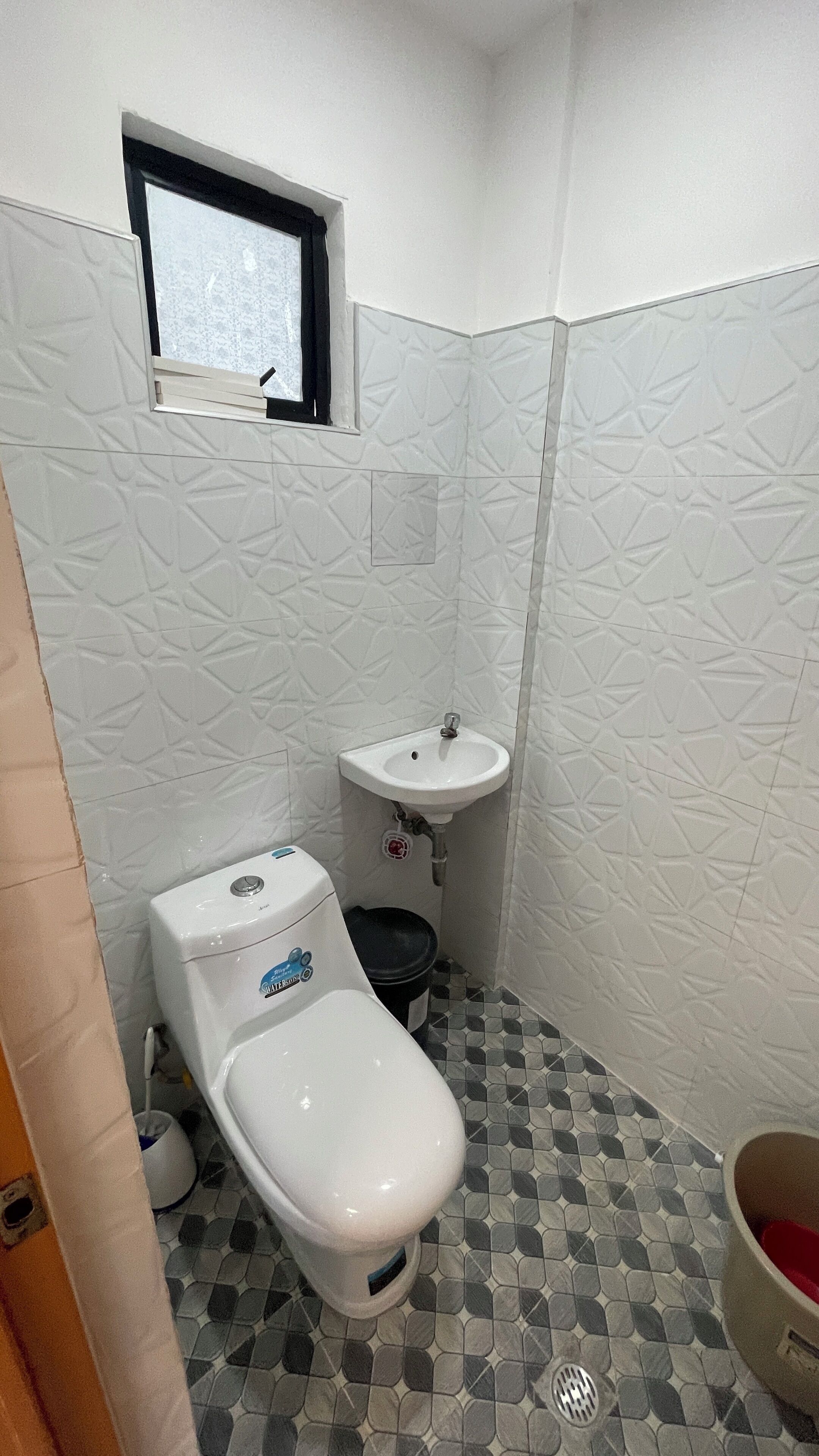 Ein kleines Badezimmer mit Toilette, Waschbecken und Fenster.