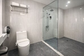 Un baño moderno con ducha de vidrio, inodoro y secamanos.