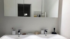 Een moderne badkamer met een grote spiegel, twee wastafels en een handdoekrek.