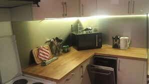 Een kleine keuken met een fornuis, magnetron en vaatwasser.