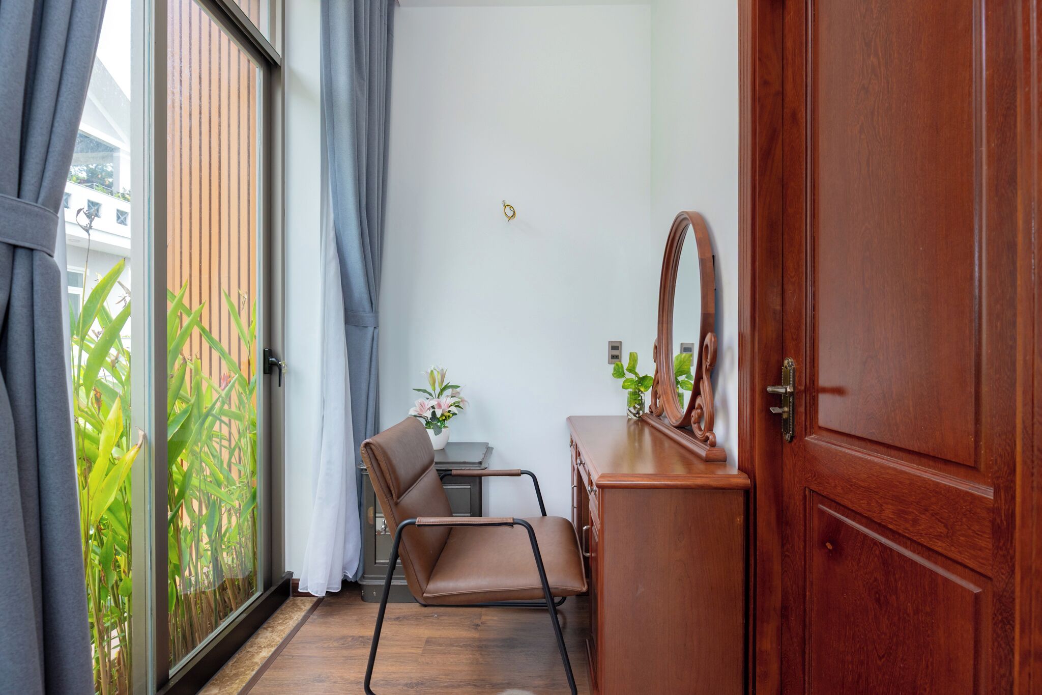 Une petite pièce avec une commode en bois, une chaise et un grand miroir.