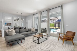 Ein modernes Wohnzimmer mit einem grauen Ecksofa, einem Holztisch und einem braunen Sessel.