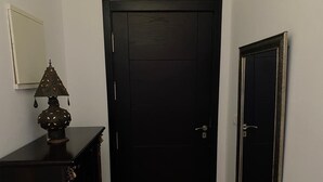 A dark wooden door with a simple design, a small table with a lamp to the left, and a mirror on the wall. - Luxury Apartment with Mountain View and Parking in Tetouan (Tétouan)