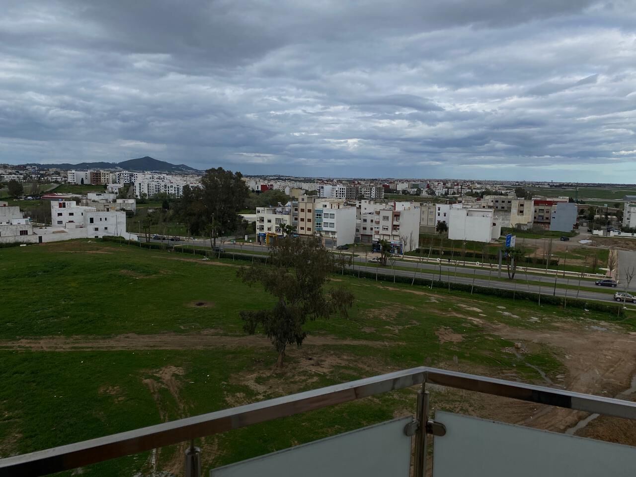 Zona residencial con edificios, un campo cubierto de césped y una calle.