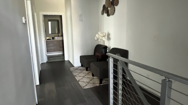 Ein modernes Interieur mit Treppe, dunklem Bodenbelag und minimalistischer Einrichtung, darunter eine Vase mit weißen Blumen.