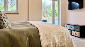 A bedroom with a bed, a television, and a sliding glass door leading to a balcony.
