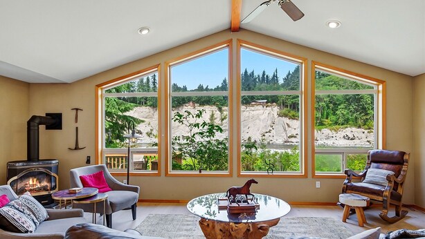 A cozy living room with a fireplace, large windows, and comfortable seating. - Prospector's Bend - Hot Tub, Riverfront, Fishing (Gold Bar)