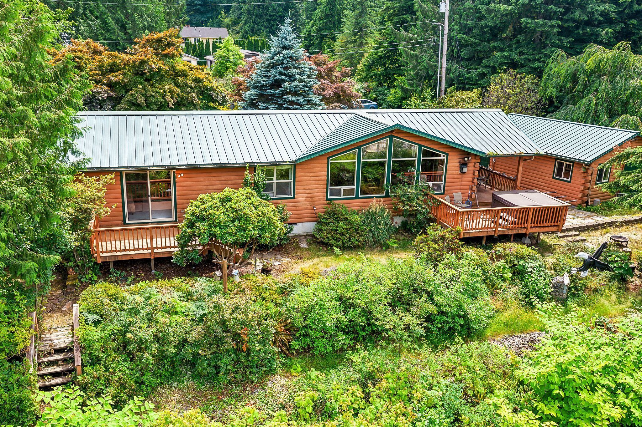 A log cabin with a metal roof, large windows, and a deck.