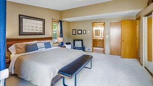 A bedroom with a large bed, a bench, a chair, a desk, and a framed picture on the wall. - Prospector's Bend - Hot Tub, Riverfront, Fishing (Gold Bar)