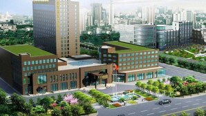 Een modern gebouw met een groen dak, grote ramen en een vlaggenmast.