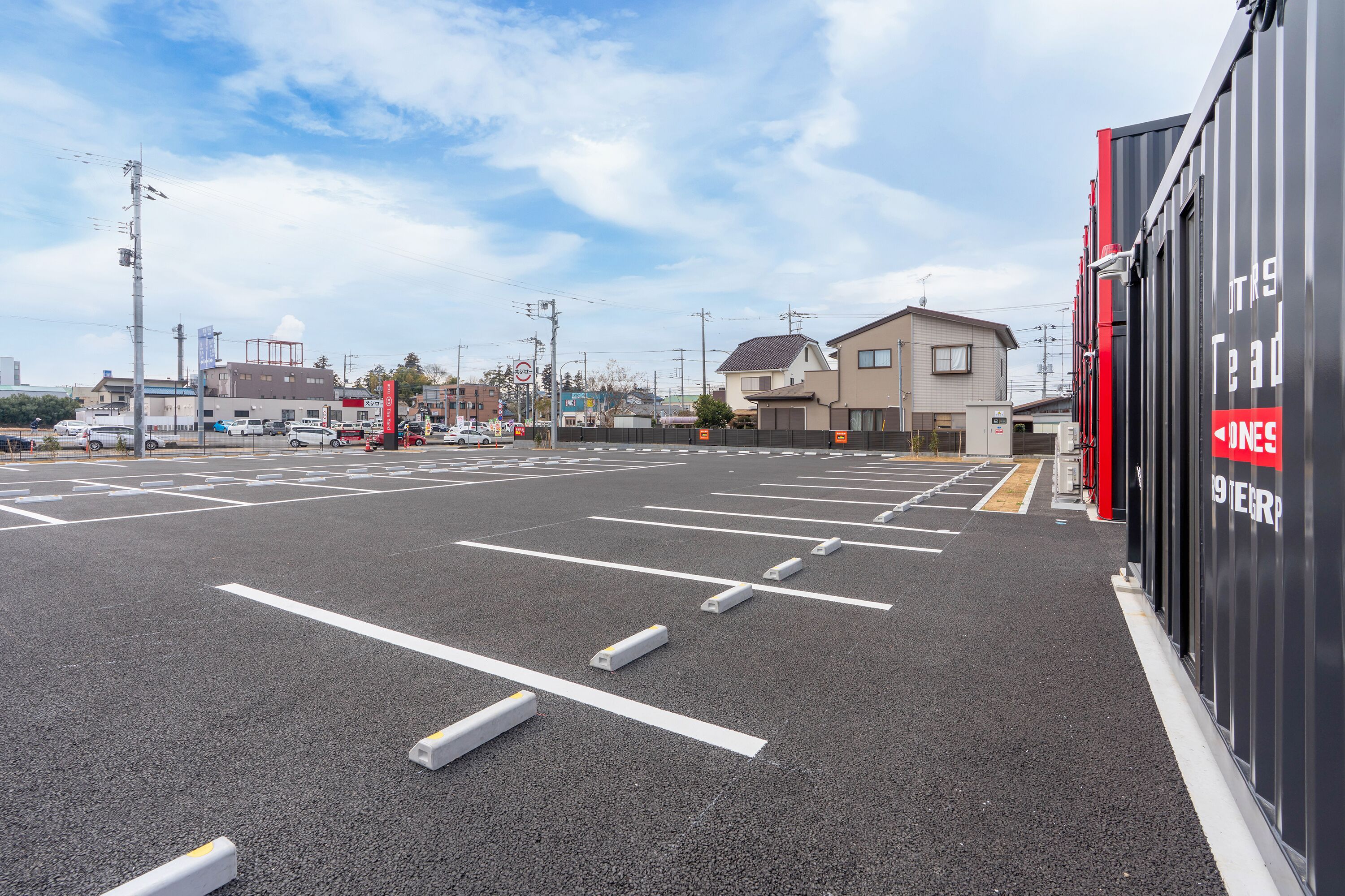 A parking lot with marked spaces and a building with signage.
