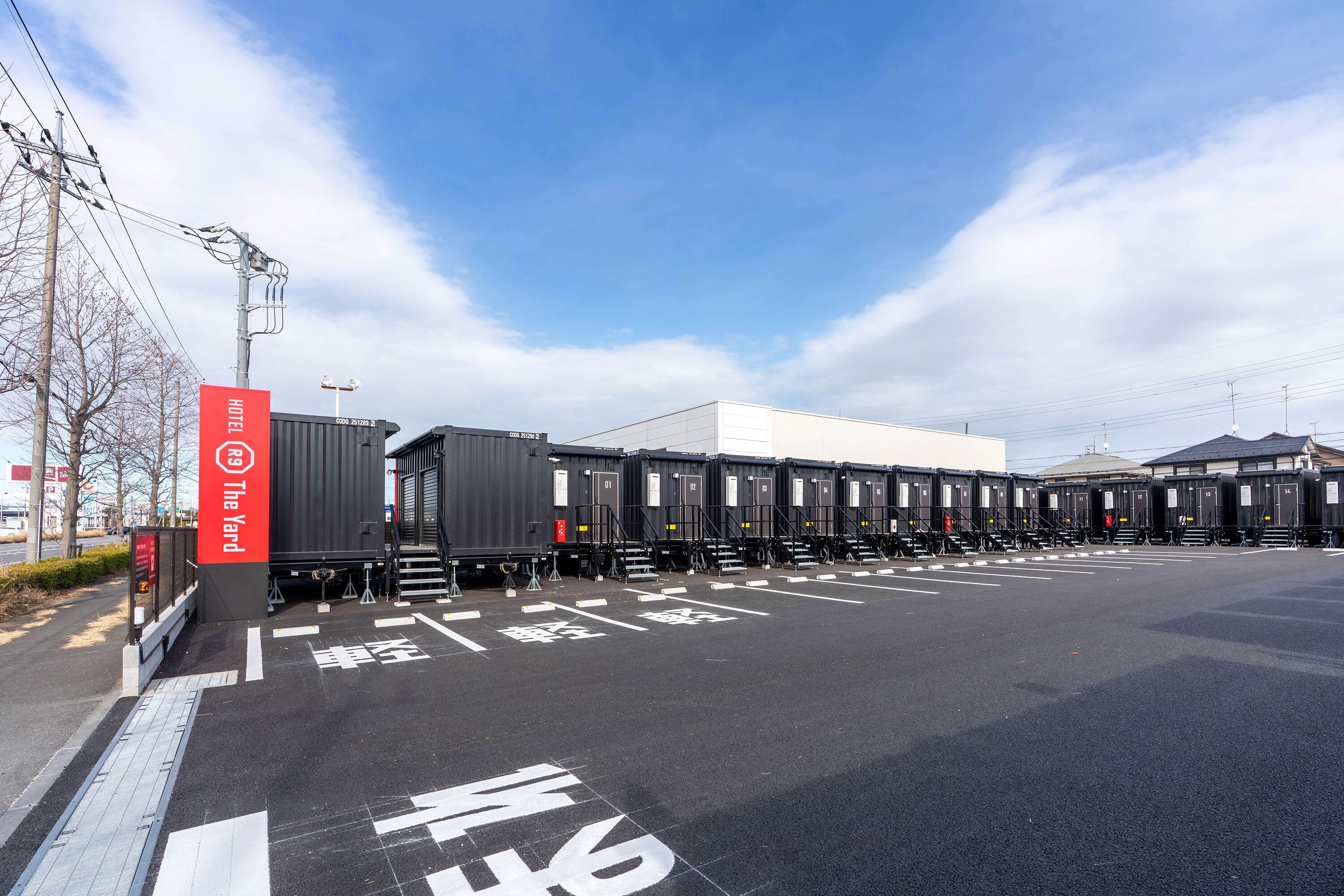 Un hotel con una fila de habitaciones estilo vagón de tren, un letrero rojo y un cielo despejado.