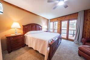 A cozy bedroom with a wooden bed, carpeted floors, and balcony access. - Eagle Point Lakeview (Joseph)