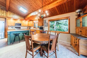 Dining and kitchen area featuring a round wood table and vaulted wood-plank ceilings. - Eagle Point Lakeview (Joseph)