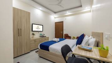 Una habitación de hotel moderna con una cama, un escritorio, una silla, un armario y un ventilador de techo.