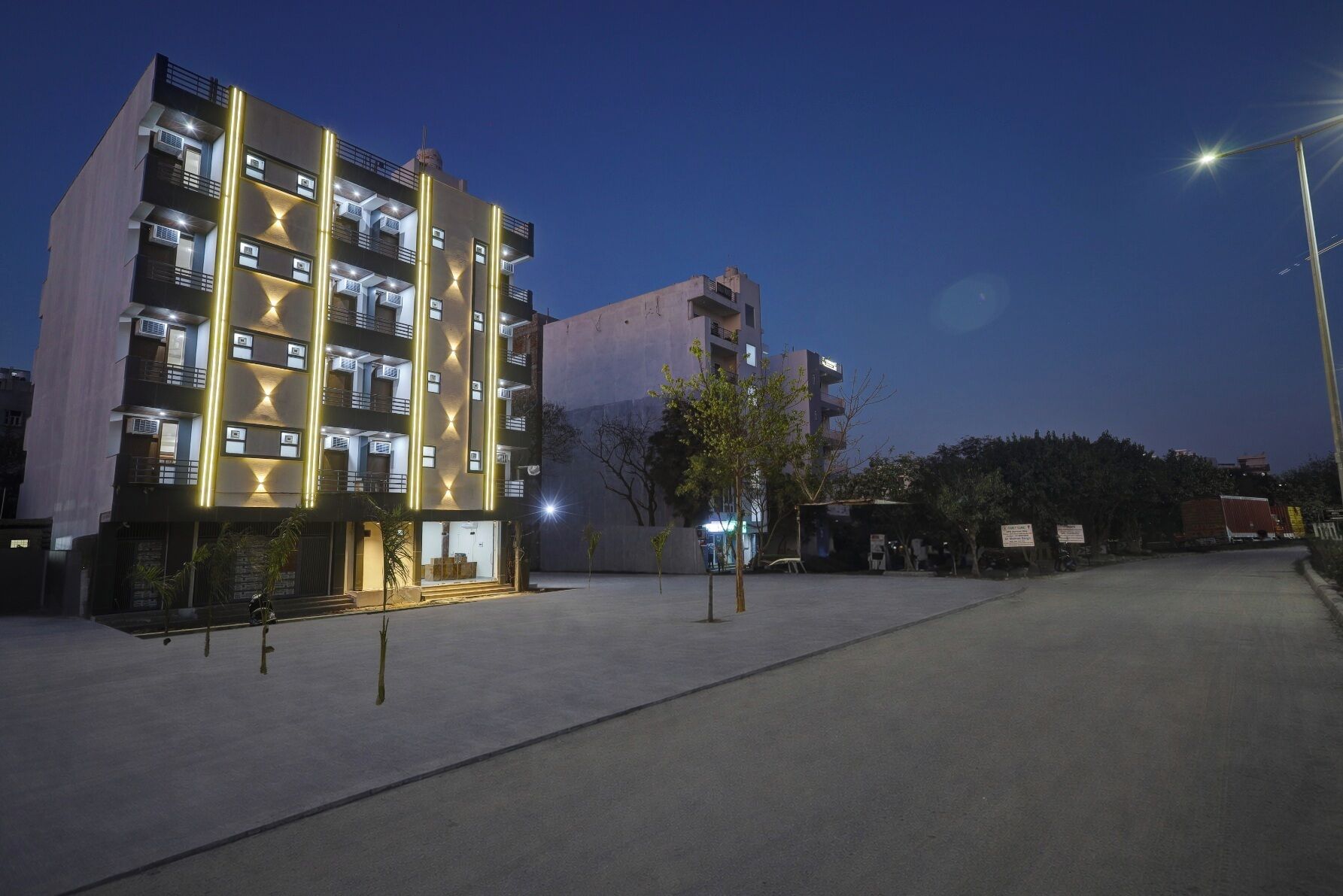 A multi-story hotel with balconies, a parking area, and a streetlight.