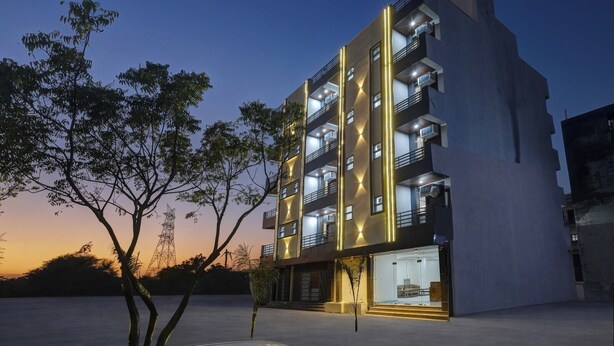 Un edificio moderno de varios pisos con balcones, entrada de vidrio y fachada bien iluminada.