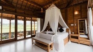 Un dormitorio con cama de dosel, muebles de madera y ventanas amplias que ofrecen vistas al exterior.