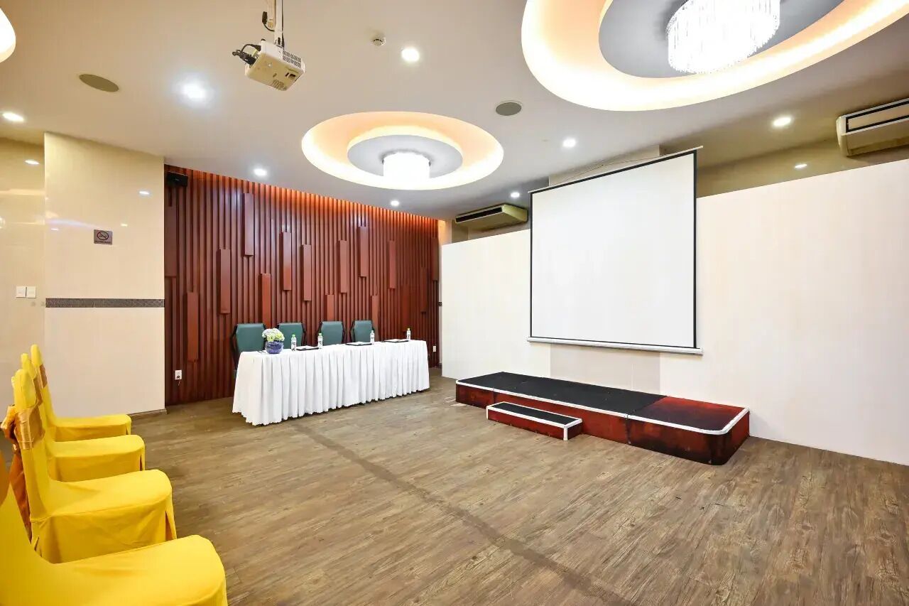 Een vergaderzaal met een whiteboard, een beamer, een tafel met stoelen en een podium.