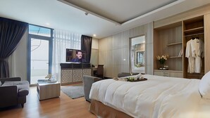 A modern hotel room with a large bed, a desk, a TV, and a wardrobe.
