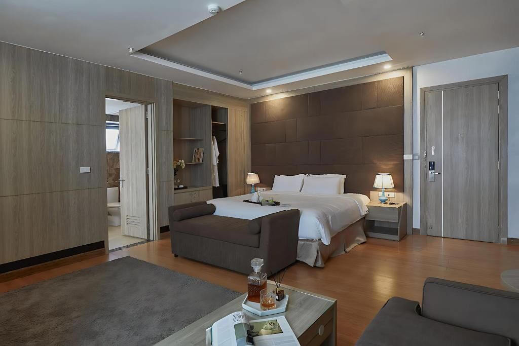 A modern hotel room with a large bed, a seating area, and a walk-in closet.