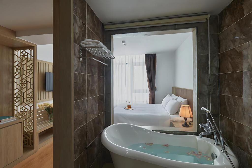 Un baño moderno con una bañera independiente, un espejo y un panel de madera con diseño geométrico.