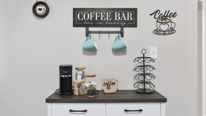 En kaffebar med en skylt, muggar, en kaffebryggare, burkar och en dekorativ väggdekoration med kaffetema.