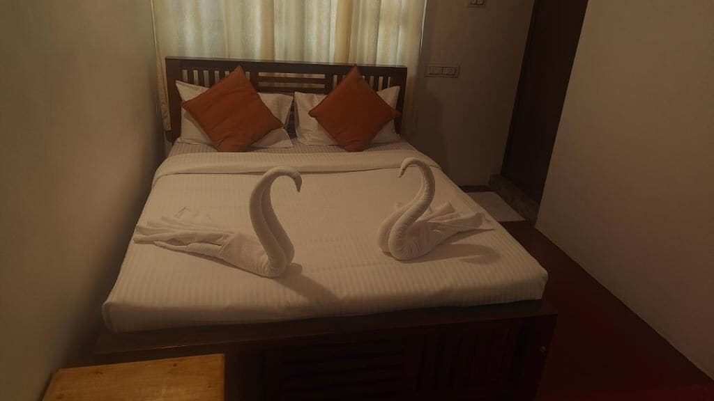 A bed with a white sheet and two orange pillows.