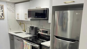 A modern kitchen with stainless steel appliances, a microwave, and a refrigerator. - A Place of Refuge and Comfort (Edmonton)