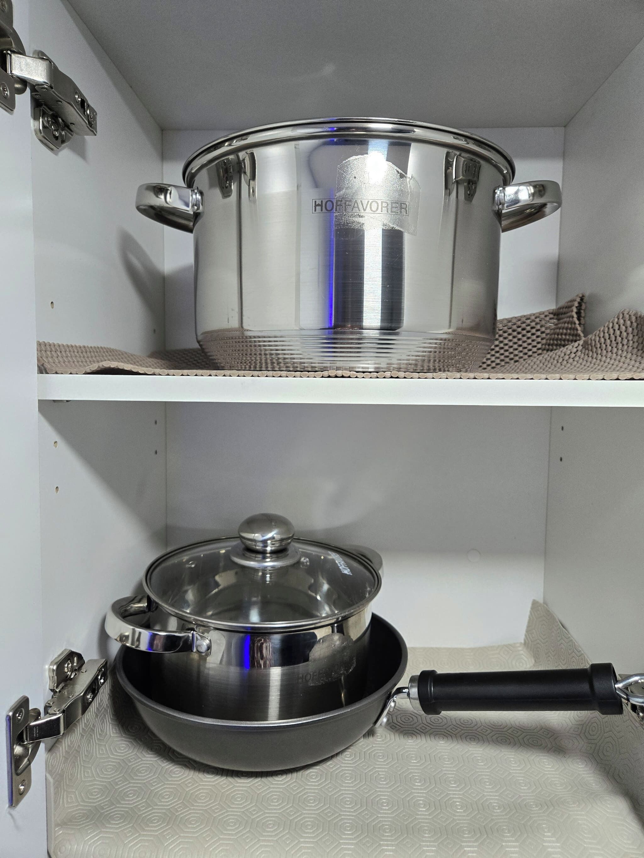 A kitchen with a pot on the upper shelf and a pan on the lower shelf.