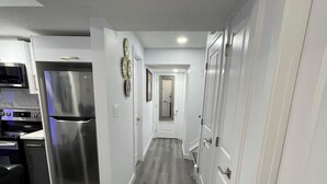 A modern kitchen with white cabinetry and a stainless steel refrigerator. - A Place of Refuge and Comfort (Edmonton)