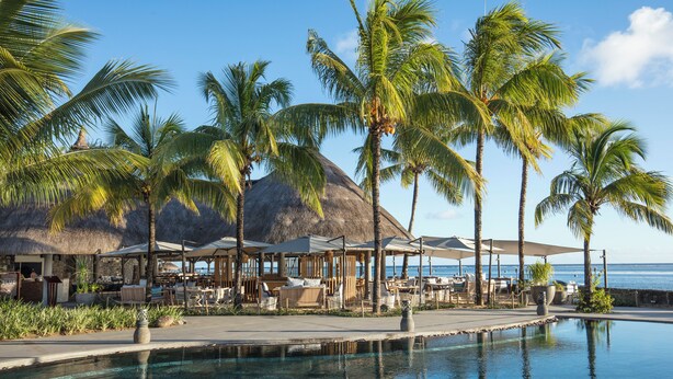 A resort pool area with palm trees, a thatched-roof structure, and a view of the sea. - Spacious 4-Bedroom Villa / Infinity Pool & Peaceful Bel Ombre Setting (Bel Ombre)