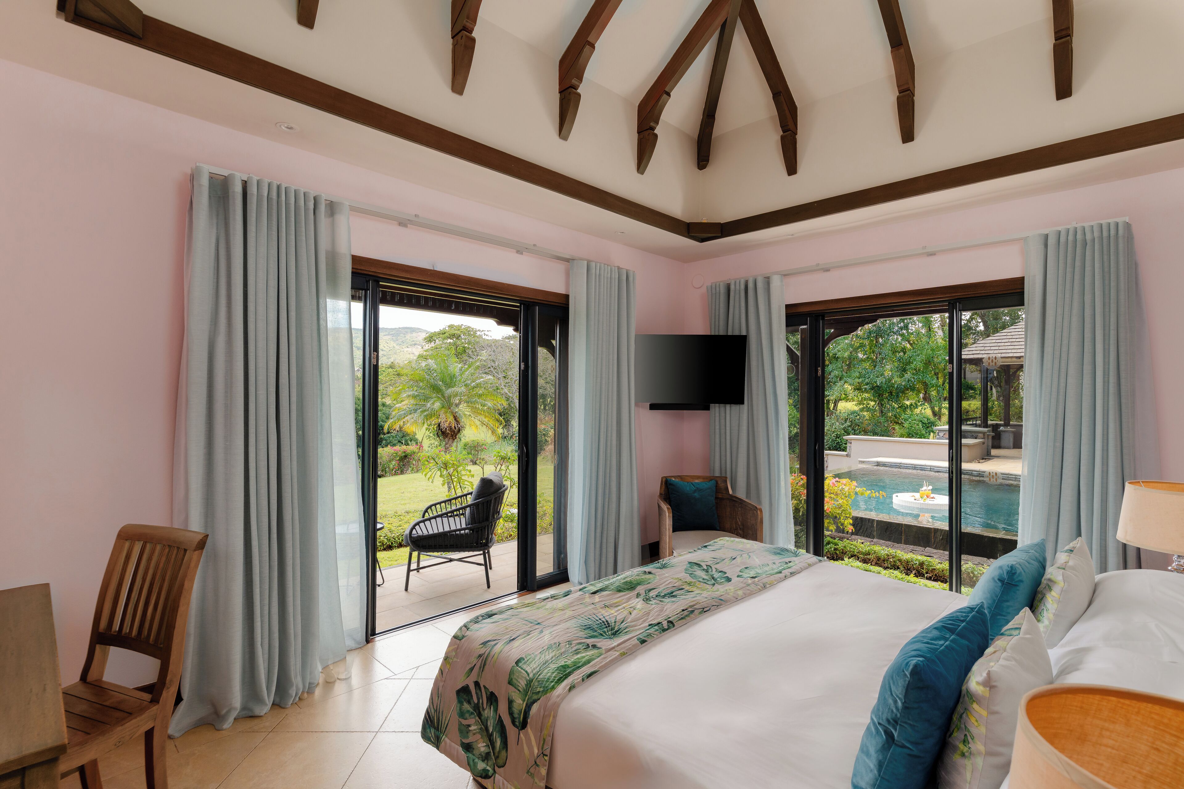 A bedroom with a large bed, a TV, and a view of a swimming pool.