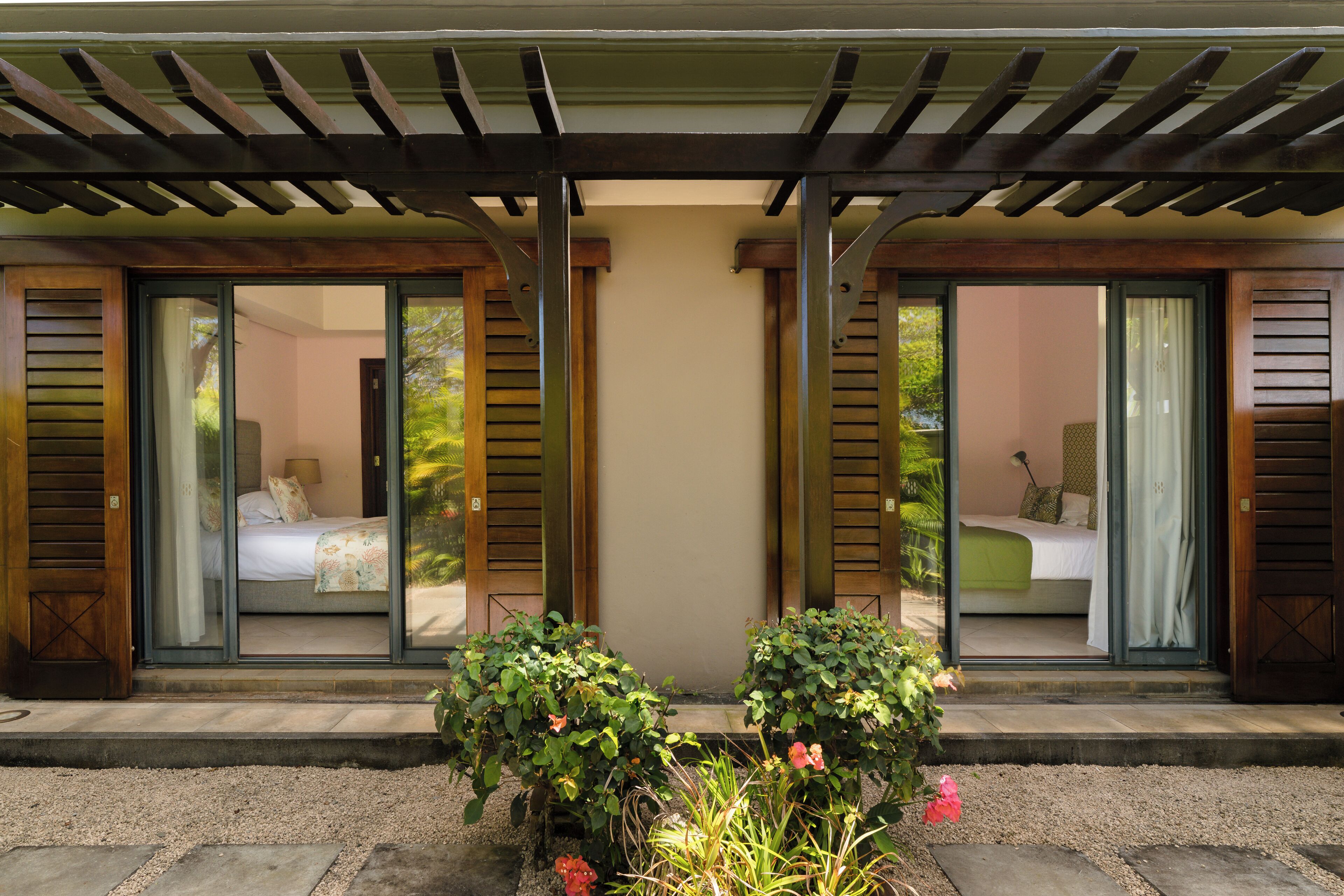 A two-room suite with sliding glass doors, a small garden area with plants, and a pergola overhead.