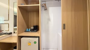 A compact hotel room with a wooden cabinet, a small refrigerator, a towel rack, and a white shower stall. - Palette Luxe Jomtien Beach Pattaya (Pattaya)