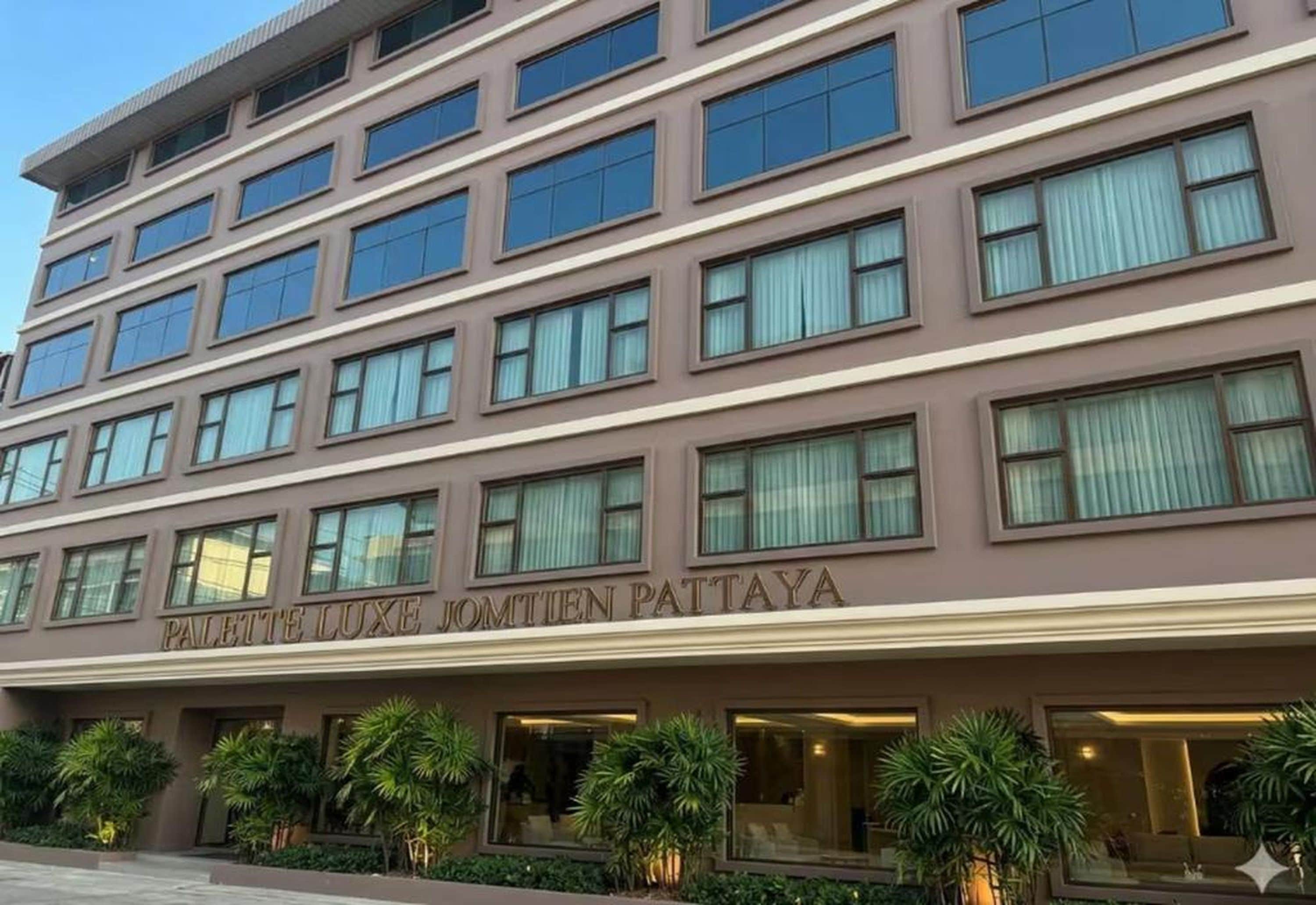 A multi-story hotel building with a modern facade, large windows, and a sign that reads 'PALACE LUXE JOMITEN PATTAYA'.