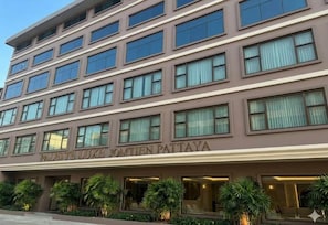 En hotelbygning med flere etager, moderne facade, store vinduer og et skilt der står 'PALACE LUXE JOMITEN PATTAYA'.