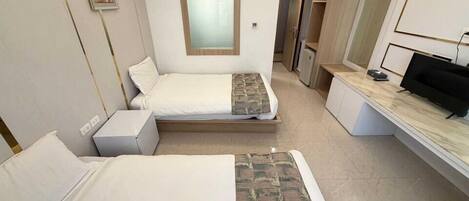 A hotel room with two beds, a desk, a TV, and a bathroom visible through an open door.