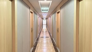 A long, narrow hallway with wooden doors on both sides, leading to a bright, well-lit end. - Palette Luxe Jomtien Beach Pattaya (Pattaya)