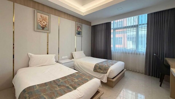 A hotel room with two beds, a desk, and a large window with curtains. - Palette Luxe Jomtien Beach Pattaya (Pattaya)