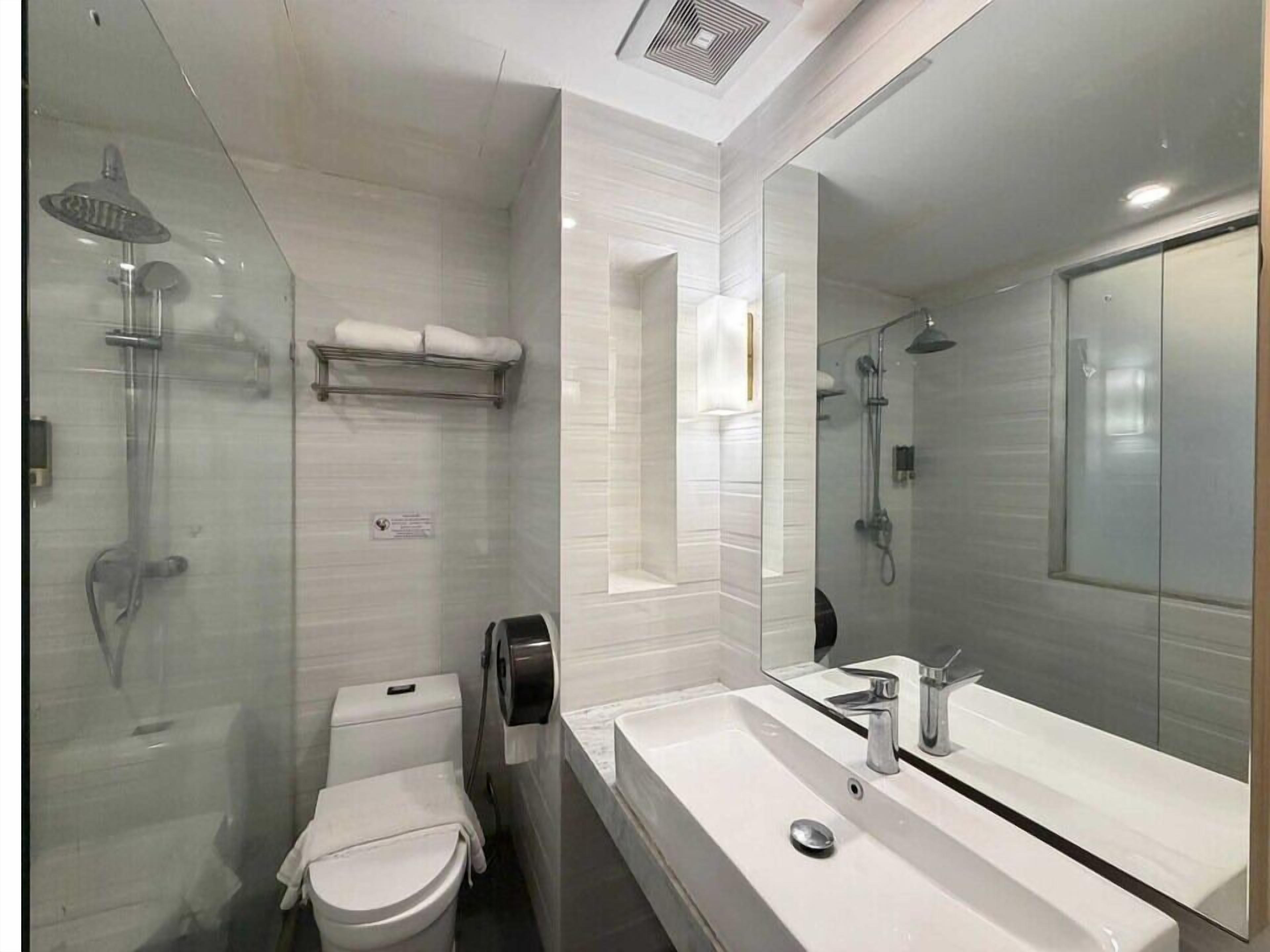 A modern bathroom with a glass-enclosed shower, a toilet, a sink with a mirror, and a towel rack.