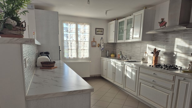 A modern kitchen with white cabinetry, a marble countertop, and a gas stove. - The gîte de la muraille welcomes you in the heart of nature, pets not allowed. (Mérignac)