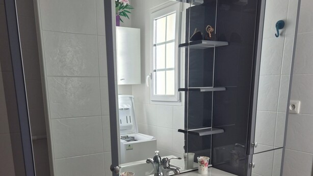 Un baño moderno con un espejo grande, un lavamanos blanco y armarios grises.