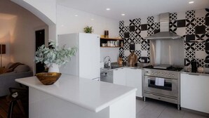 Een moderne keuken met witte kasten, een centraal eiland, een inbouwoven en een decoratieve spatwand.
