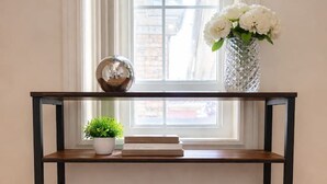 A wooden console table with two wicker baskets underneath, a small potted plant, and a vase with white flowers on top. - Above-Ground · Sun-Filled · Not a Basement · Your Own Private Entrance (Brampton)